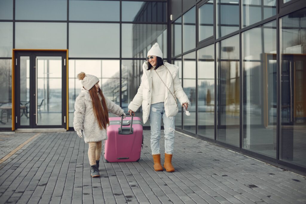 mother and daughter with luggage going from airport terminal